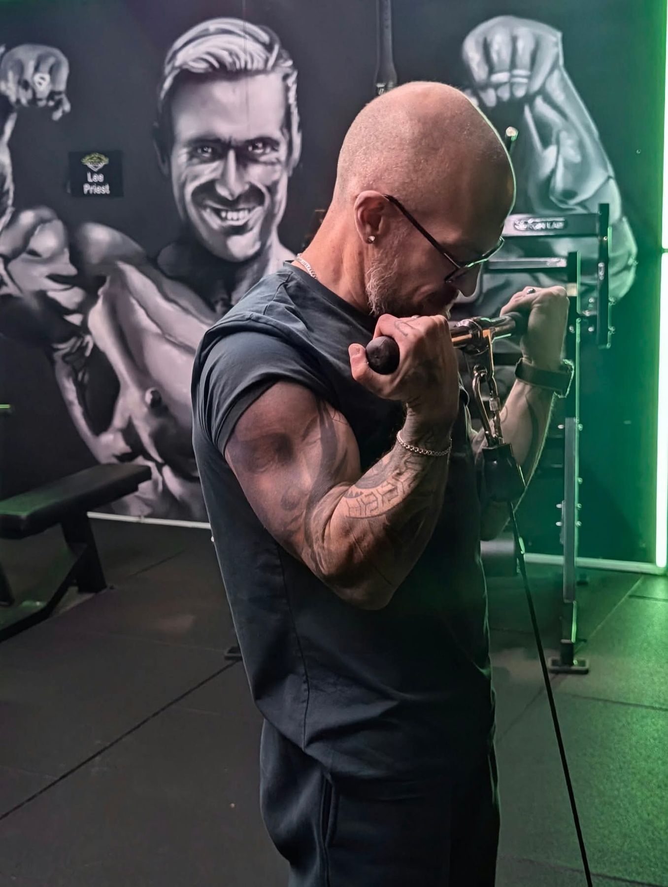 A member doing bicep curls in front of a painted mural wall