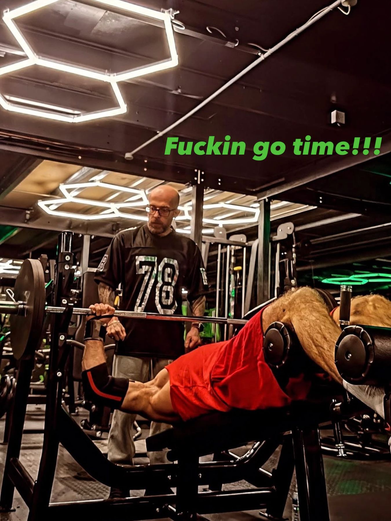 A lifter on the incline press with a spotter standing behind